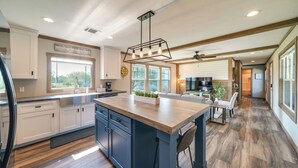 A spacious kitchen with a large island, wooden flooring, and a welcoming sign. - Pet-friendly Hill Country Hideaway w/ Deck (D'Hanis)