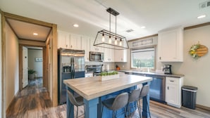 A modern kitchen with a central island, stainless steel appliances, and a large window providing natural light. - Pet-friendly Hill Country Hideaway w/ Deck (D'Hanis)