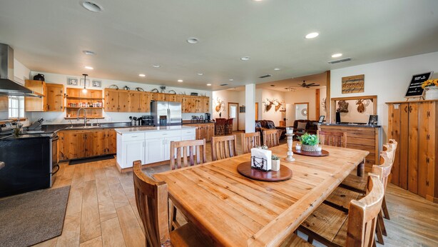 A spacious kitchen with wooden cabinets, a large dining table, and a refrigerator. - Texas Nature Escape: Lake & Game Room Access (D'Hanis)
