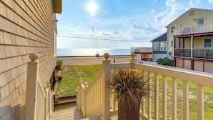 A wooden deck with a railing, a potted plant, and a view of the beach and ocean. - Lovely Coastal Home By Delaware Bay: Walk to Beach (Fortescue)