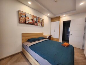 Un dormitorio con cama, mesita de noche, un cuadro en la pared y una puerta que da a un baño.