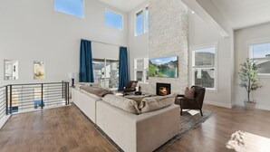 A spacious living room with a large sectional sofa, a fireplace, and a view of a mountain landscape. - Deer Springs by Park City Vacations (Heber City)
