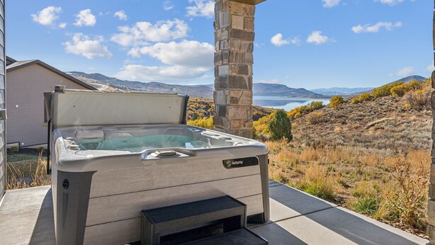A hot tub under a covered patio with a scenic view of mountains and a lake. - Deer Springs by Park City Vacations (Heber City)