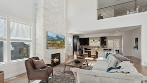 A spacious living room with a fireplace, a large sofa, and a dining area. - Deer Springs by Park City Vacations (Heber City)