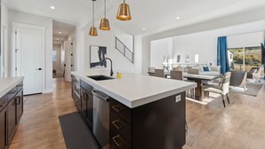 A modern kitchen with a central island, pendant lighting, and a view to a dining area. - Deer Springs by Park City Vacations (Heber City)