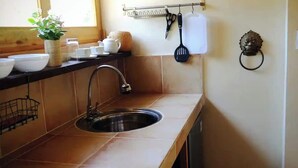 Eine Küche mit einer Spüle aus Edelstahl, einem Küchenutensilienständer und einem dekorativen Wandbild.