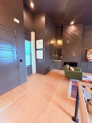 A modern living room with a green armchair, a wooden coffee table, and a fireplace.