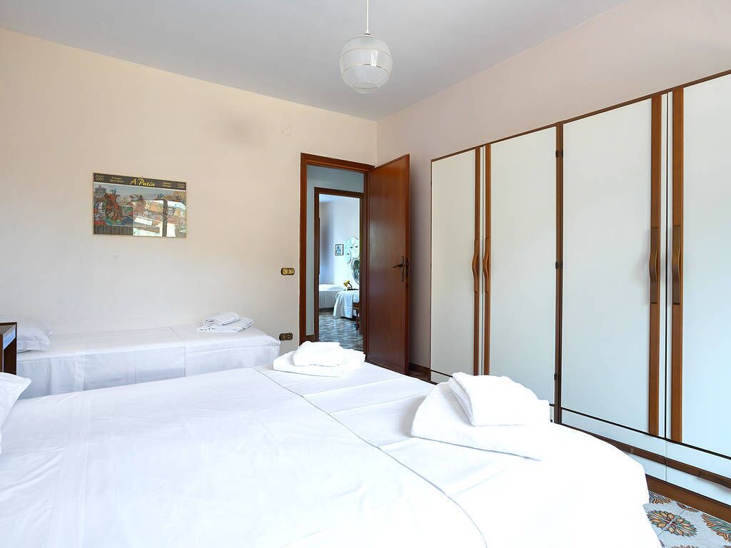 A hotel room with two beds, a wardrobe, and a door leading to a bathroom.