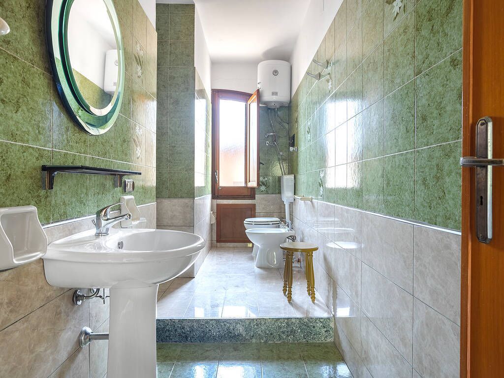 A bathroom with a sink, mirror, toilet, and bidet.