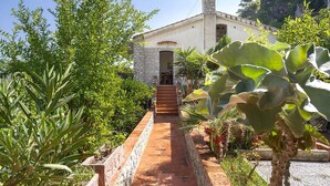 A building with a stone facade, a chimney, and a pathway leading to the entrance. - Solemar Sicilia - Villa Corallo (Bagheria)