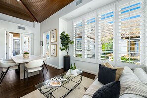 Relax in this spacious living area with a high ceiling and dining space, featuring a sofa and a large potted plant.