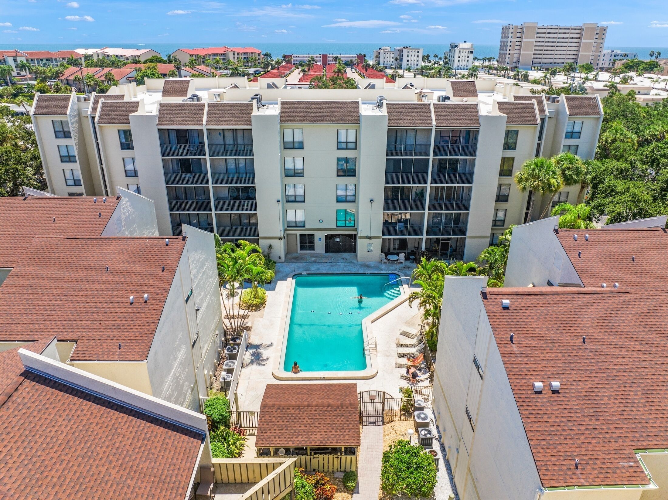 A multi-story hotel with a central swimming pool surrounded by balconies and outdoor seating.