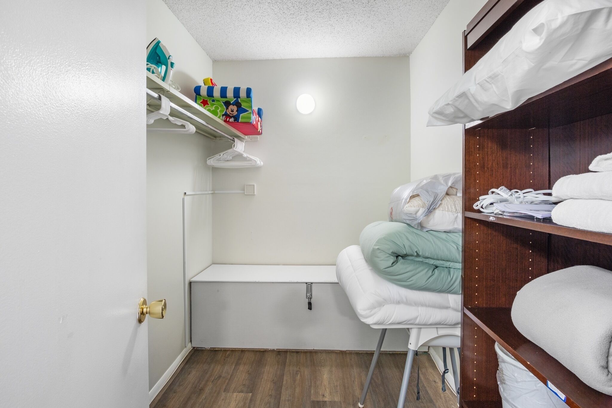 A compact room with a built-in bench, a shelf with toys, and neatly stacked towels.