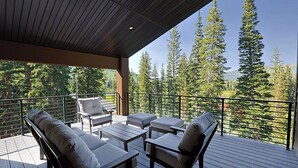 Une terrasse extérieure couverte, dotée de sièges et offrant une vue sur de grands arbres.