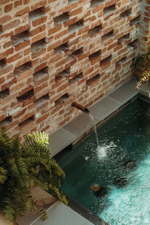Een bakstenen muur met een waterpartij, inclusief een pijp en een zwembad.