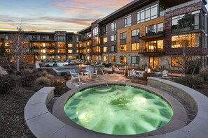 A modern hotel with a heated outdoor pool, lounge chairs, and a well-lit courtyard. - Luxury 2 Bedroom Ski in Ski Out 2 Condo (Park City)