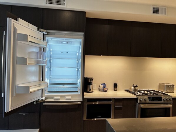 A modern kitchen with a built-in refrigerator, a gas stove, and a dishwasher.