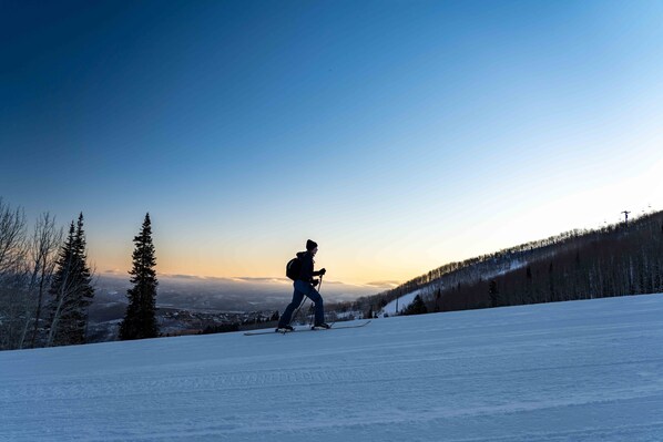 A person skiing down a snow-covered slope with a clear sky in the background.