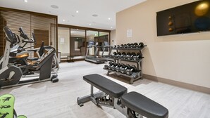 Ein Fitnessraum mit Laufbändern, Gewichten und Bänken.