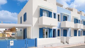 Un edificio moderno de varios pisos con balcones, paredes blancas y contraventanas azules.