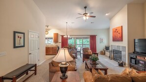 A spacious living room with a fireplace, a television, and a dining area with a chandelier. - Lakefront Lodge by Innsbrook Vacations! (Innsbrook)