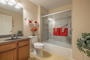 A bathroom with a toilet, sink, and bathtub. There are towels and a shower curtain. - Lakefront Lodge by Innsbrook Vacations! (Innsbrook)