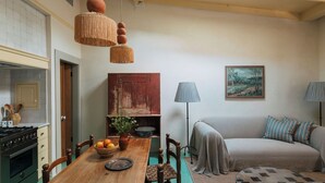 A cozy living room with a sofa, a dining table with chairs, a lamp, and a painting on the wall. - Designer Bywater Carriage House w/ Pool & Courtyard Near Frenchmen (New Orleans)