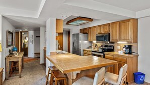 A compact kitchen with wooden cabinets, a central island, and modern appliances.