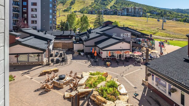 A hotel courtyard with outdoor seating, a restaurant, and a view of a mountain.