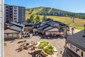 A hotel courtyard with outdoor seating, a restaurant, and a view of a mountain. - At the Base of the Mtn | Fireside + Shuttle (Steamboat Springs)