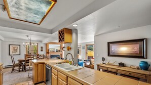 A spacious kitchen with wooden cabinets, a large island with a sink, and a dining area with chairs.