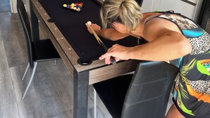 A pool table in a modern kitchen with white cabinets and a built-in oven.