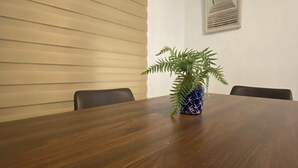 A conference room with a wooden table, chairs, a potted plant, and a framed picture on the wall. - Waves & Chill 1 | Jobos Guest House (Isabela)