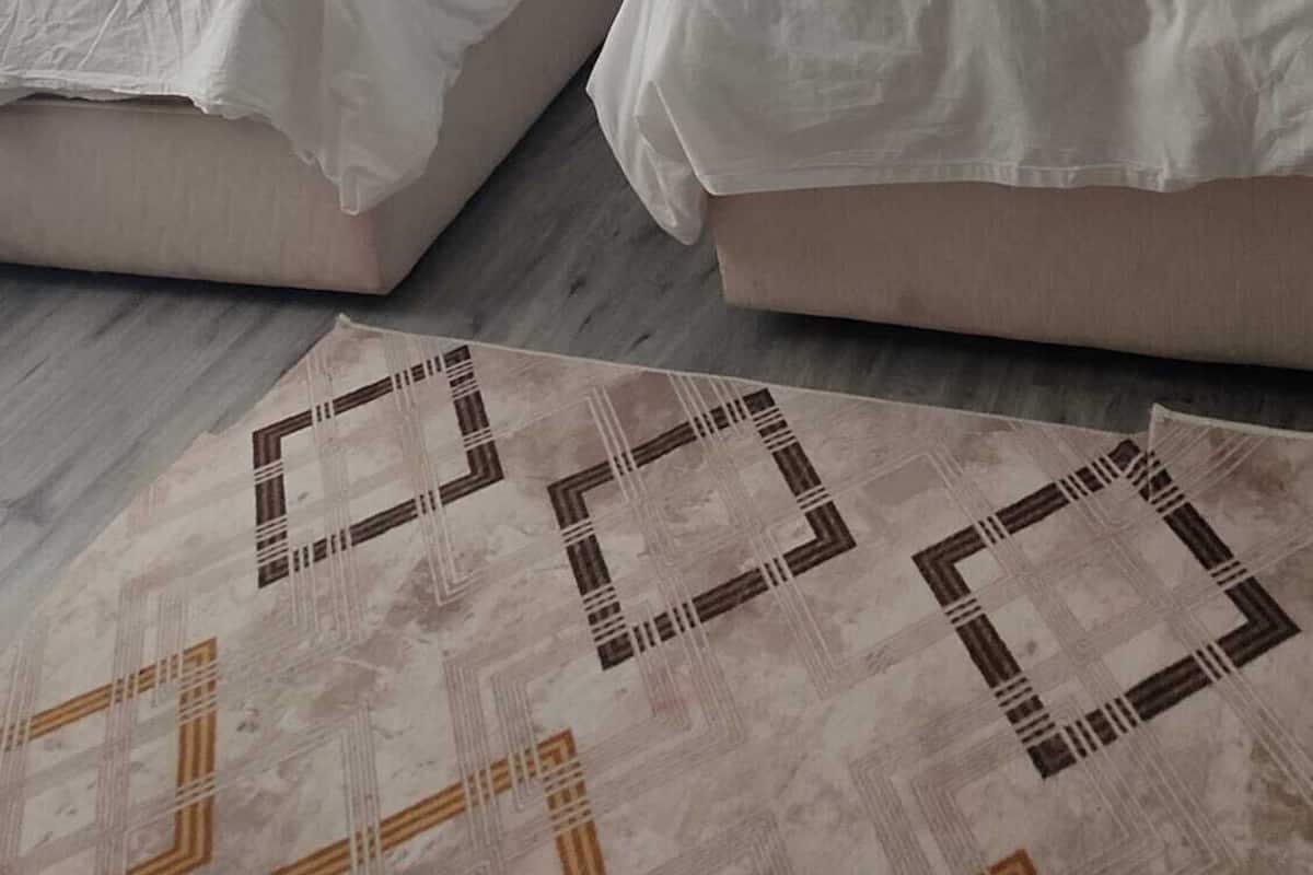A room with two beds, a patterned rug, and a blue wall.