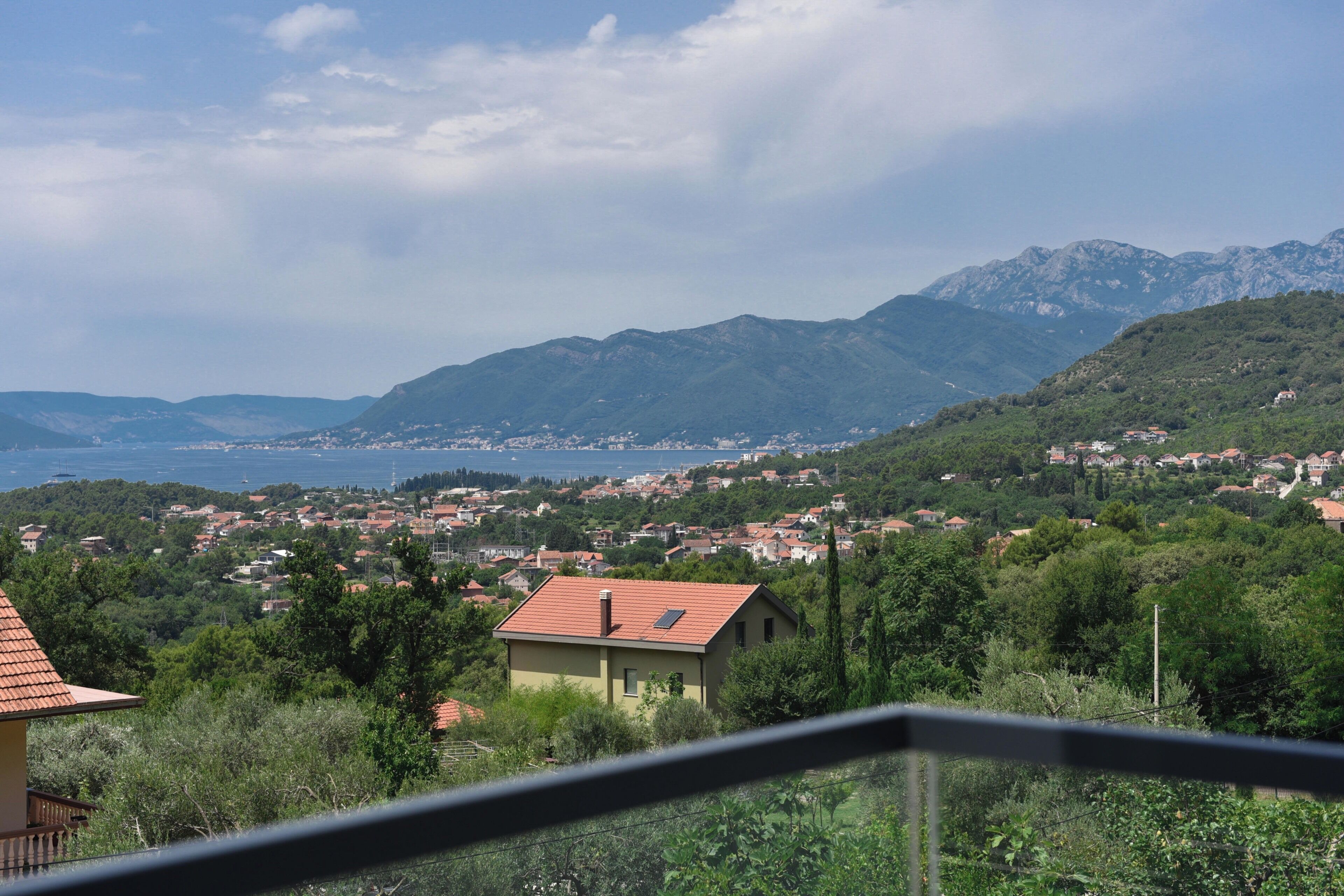 A coastal town with houses, mountains, and a view of the sea.
