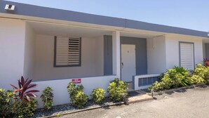 Un motel su due piani con un portico coperto, un segnale che indica 'Divieto di parcheggio' e piccoli vasi di piante lungo il vialetto.
