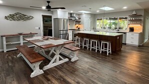 Una cocina moderna con una isla central, taburetes de madera y una mesa con bancos.