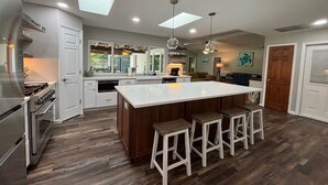 Una cocina moderna con una isla central, taburetes de bar y una zona de comedor.