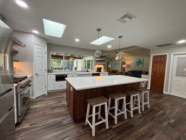 A modern kitchen with a central island, bar stools, and a dining area.