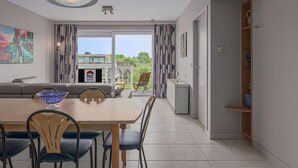 A modern dining area with a wooden table, chairs, and a blue glass bowl centerpiece. - 1 bedroom accommodation in Oostduinkerke (Oostduinkerke)