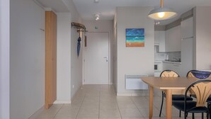 A modern interior with a wooden door, a dining area with a table and chairs, and a kitchen in the background. - 1 bedroom accommodation in Oostduinkerke (Oostduinkerke)