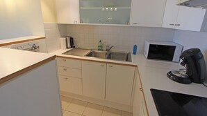 A kitchen with white cabinets, a microwave, a coffee maker, and a sink. - 1 bedroom accommodation in Nieuwpoort (Nieuwpoort)