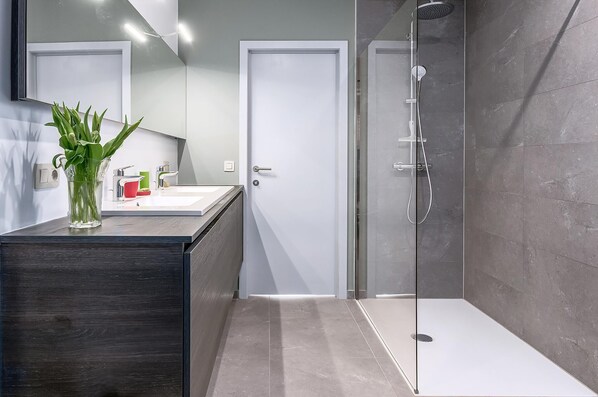 A modern bathroom with a glass shower enclosure, a dark wooden vanity, and a mirror above the sink.