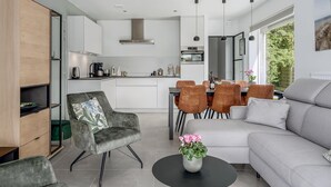 A modern kitchen with white cabinets, a dining area with orange chairs, and a grey sofa. - 2 bedroom accommodation in Oostduinkerke (Oostduinkerke)