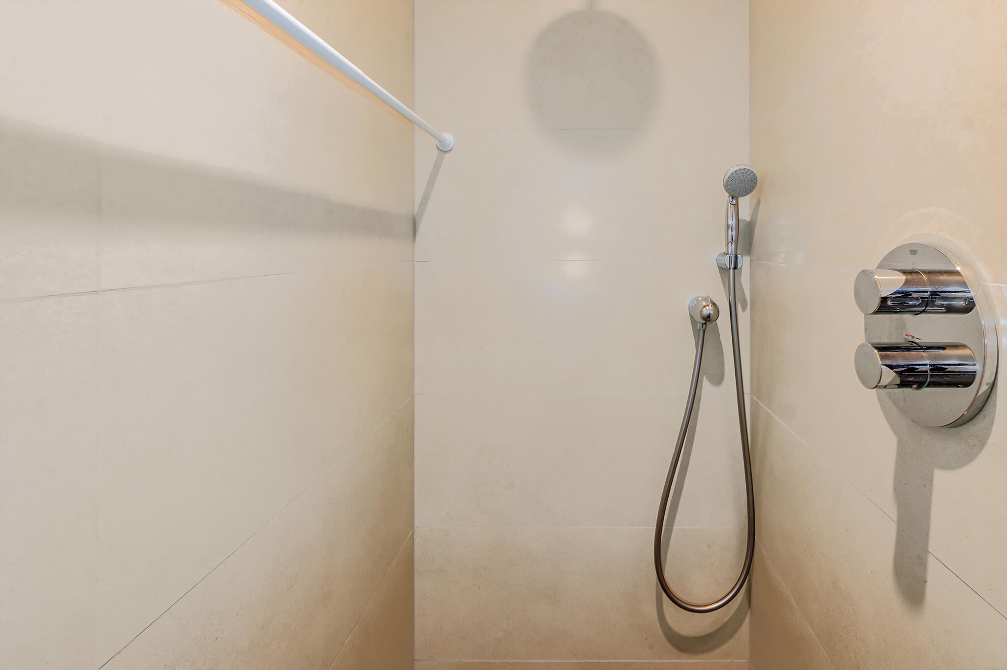 Una ducha moderna con cabezal de ducha de mano y grifo empotrado.