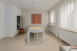 Ein geräumiger Raum mit einem langen Tisch, einem Bücherregal und einem großen abstrakten Gemälde an der Wand.