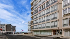 Et hotel med flere etager, med altaner, store vinduer og udsigt til havet.