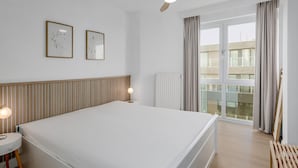 Et hotelværelse med en stor seng, loftsvifte, radiator og udsigt til det fri gennem et stort vindue.