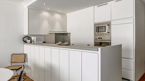 A modern kitchen with white cabinetry, a central island, and a built-in oven. - 2 bedroom accommodation in Sint Idesbald (Sint Idesbald)