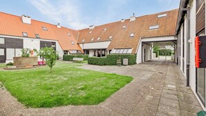 A courtyard with a paved walkway, a small lawn, and buildings with tiled roofs and windows. - 2 bedroom accommodation in Nieuwpoort (Nieuwpoort)